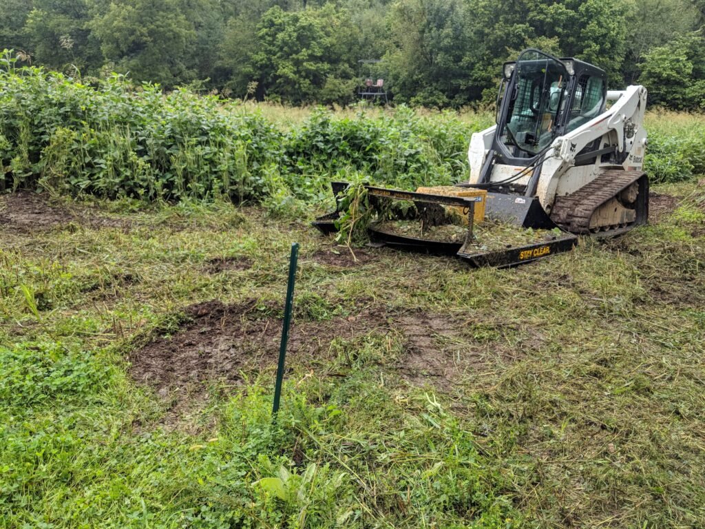 A white vehicle is clearing the land.